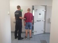Policjant wprowadza zatrzymanego do celi