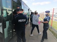 Policjanci rozdają ulotki informujące pasażerom wysiadającym z autobusu