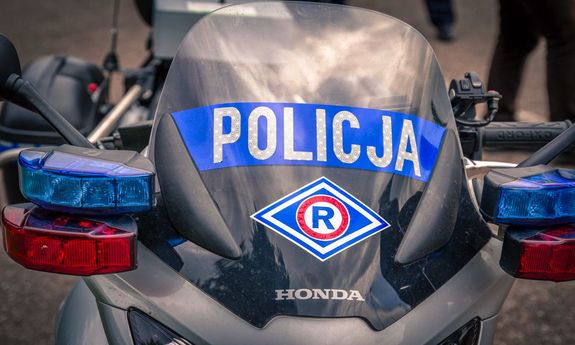 Przód policyjnego motocykla z napisem &quot;POLICJA&quot; i logo wydziału ruchu drogowego na przedniej szybie.