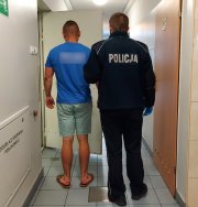 Policjant wprowadza zatrzymanego mężczyznę do celi.
