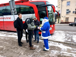 Policyjny Mikołaj rozdaje upominki mieszkańcom przy autobusie krwiodawczym