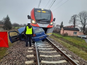 Miejsce wypadku, widać pociąg, samochód i stojącego policjanta