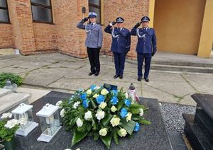 policjanci składają kwiaty na grobie policjanta